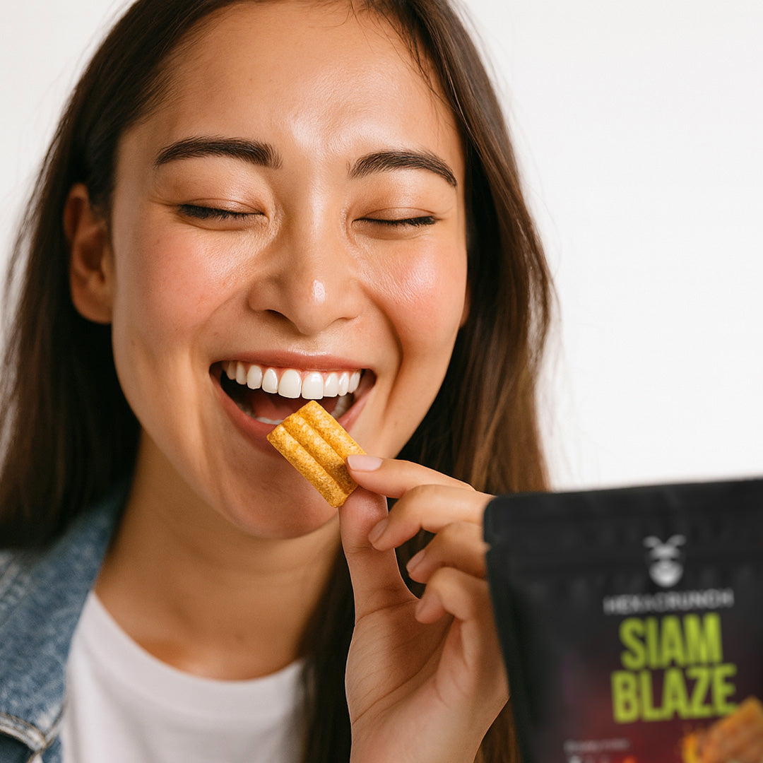 Woman enjoying HexaCrunch Siam Blaze Tom Yum – cricket protein crackers with golden crunch and bold flavour.