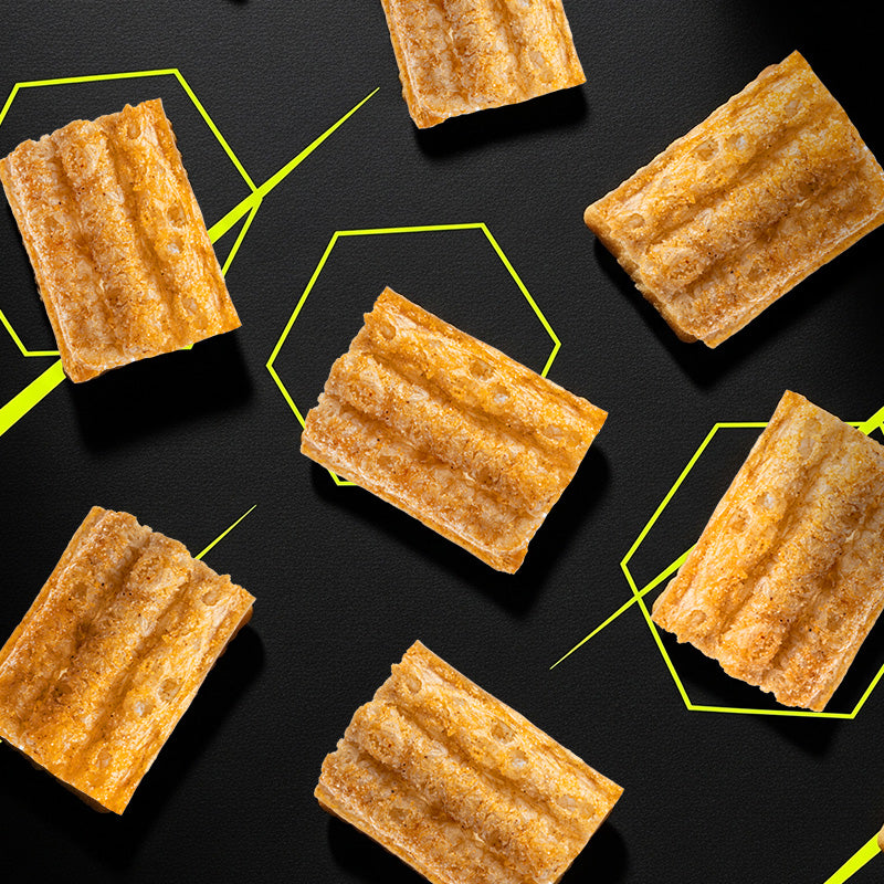 Close-up of HexaCrunch cricket-protein rice crackers – crispy baked insect snack pieces on black background with neon accents.