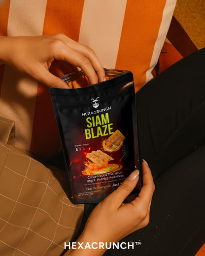 Person holding a HEXACRUNCH Siam Blaze snack package with a striped background